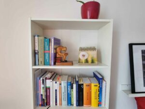 Bücherregal mit Büchern, einem Spruchkalender und Blumentopf