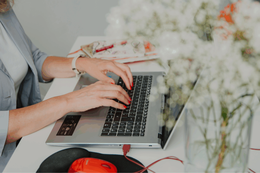 Frau schreibt an Tastatur mit Blumen davor.